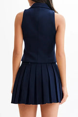Back view of a woman wearing a navy blue sleeveless blazer vest and pleated skirt.