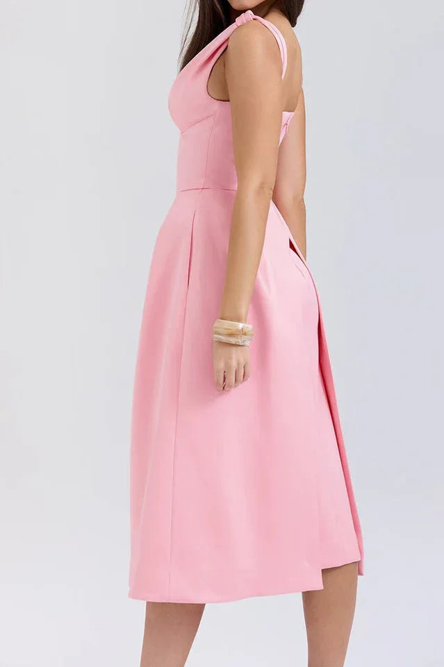 Side view of a woman in a pink midi dress with a fitted bodice and A-line skirt.