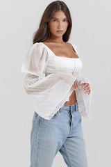 Close-up of the details on the white cropped blouse, highlighting the neckline and sleeves