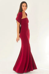 Woman wearing a red strapless mermaid gown with a scarf styled as a shawl over her shoulders