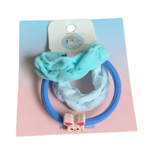 Set of two blue scrunchies with a pink bunny charm on a blue hair tie, presented on a pastel pink and blue card.