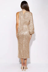 Woman in a gold sequin one-shoulder midi dress with a high neckline and a side slit, shown from the back.