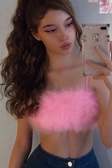 Woman in a pink fuzzy crop top and denim jeans taking a selfie