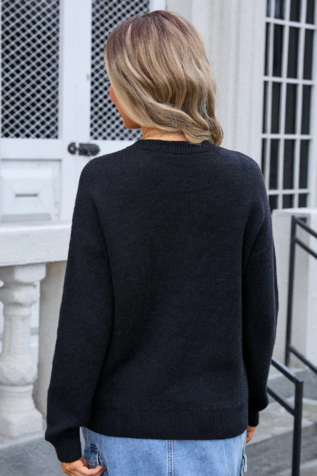 back view of woman wearing black crew neck sweater with white bow pattern