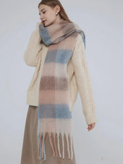 Woman wearing a cream cable knit sweater and a plaid scarf, looking over her shoulder.