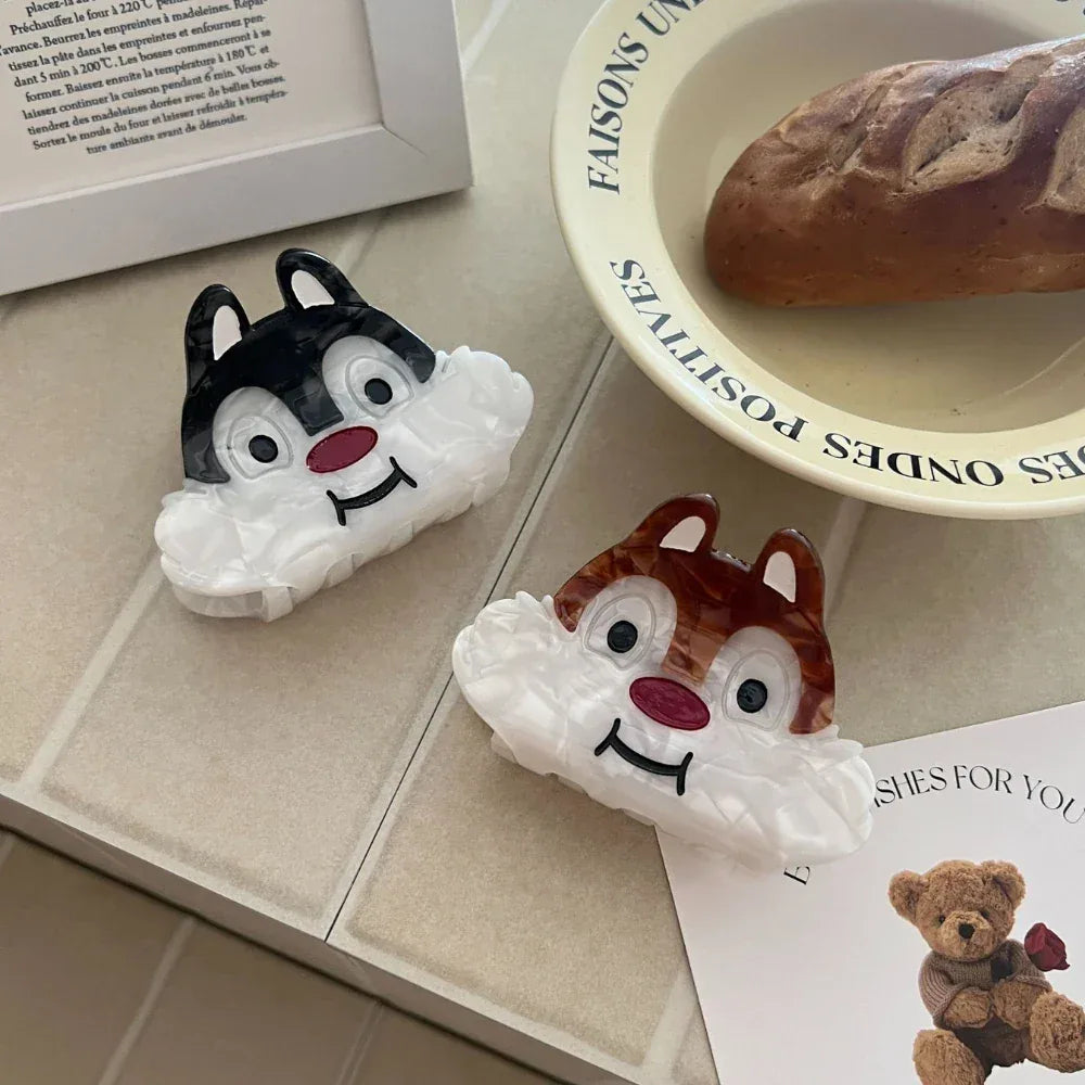 Two cartoon chipmunk face hair claw clips on a tiled surface with a bread bowl
