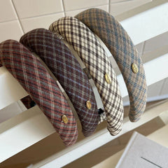A row of plaid padded headbands resting on a white surface