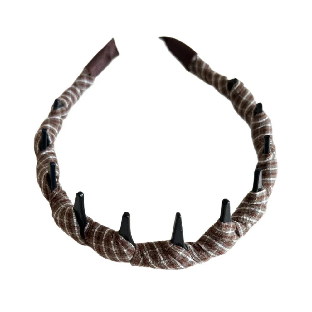 A brown and white plaid fabric-wrapped headband with black interlocking teeth