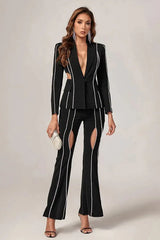 Woman in a black suit with cut-out details and decorative trim, holding a clutch.