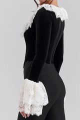 Woman wearing a black velvet top with white lace trim and ruffled collar and cuffs, side view
