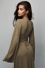 Back view of a woman wearing a long-sleeved, ribbed maxi dress with bell sleeves, showing lace-up detail at the waist in a taupe color.