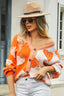 Woman wearing an orange and pink colorblock strawberry print knit cardigan with a V-neckline and button-up closure.
