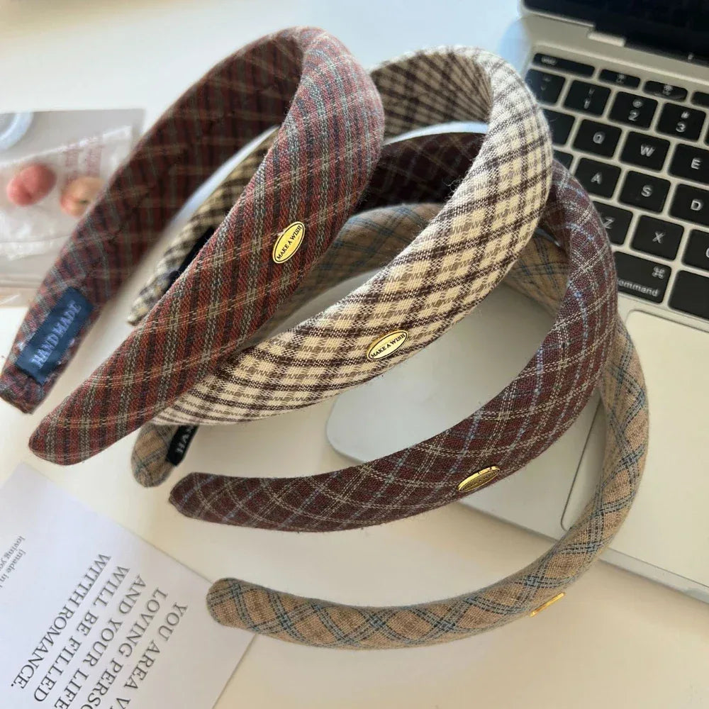 Several plaid padded headbands arranged on a desk near a laptop