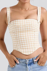 Woman wearing a beige and white gingham corset top with denim jeans.