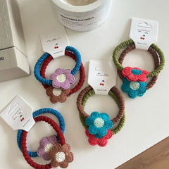 Various crocheted flower hair ties arranged on a white surface.