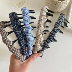 A collection of plaid fabric-wrapped headbands with black interlocking teeth in various colors
