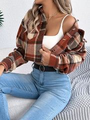 Model sitting down wearing a cropped plaid jacket, white tank top, and blue jeans.