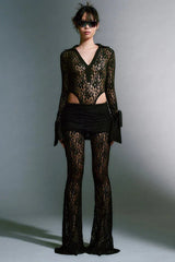 Model wearing a black lace bodysuit with flared pants and a mini skirt overlay.