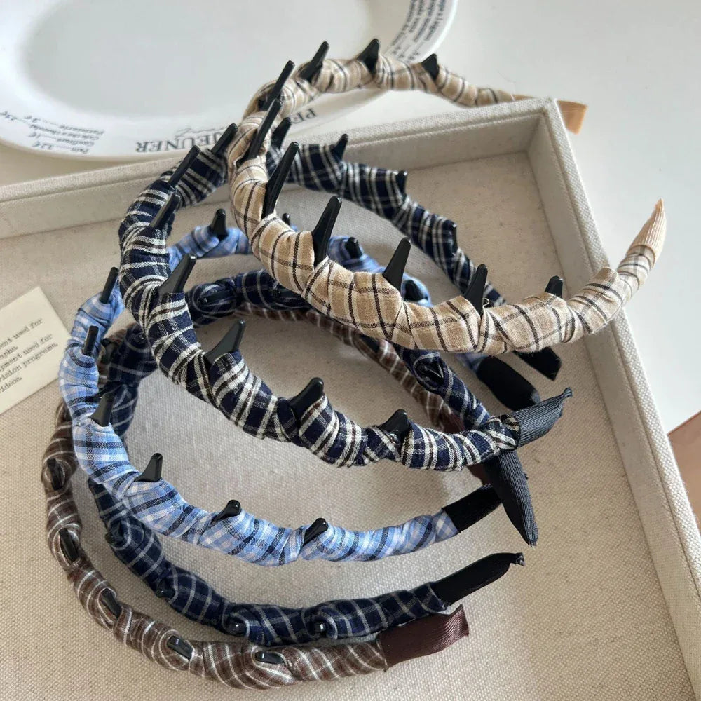 Several plaid fabric-wrapped headbands with black interlocking teeth arranged in a tray