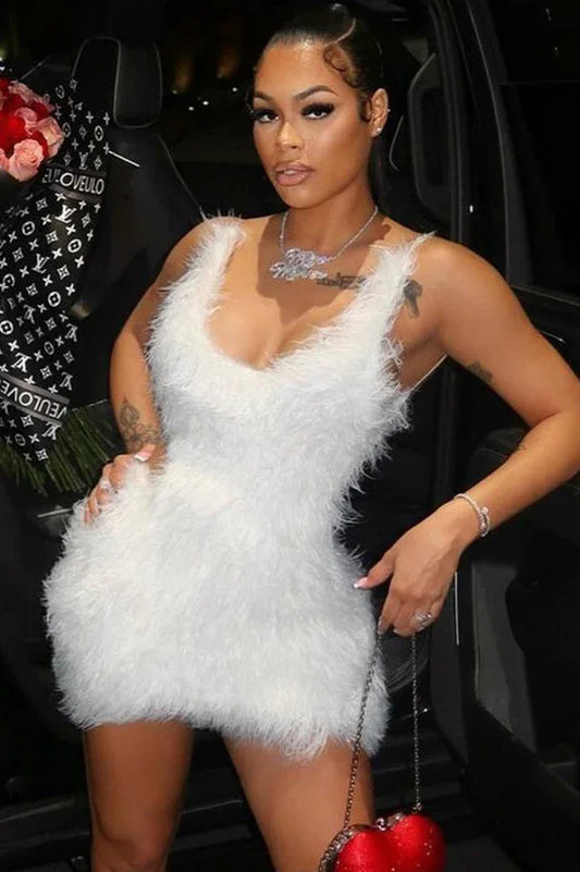 Woman wearing a white fluffy mini dress and holding a red heart-shaped purse.