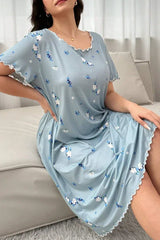 Woman wearing a light blue floral print nightgown with scalloped trim, sitting on a sofa.