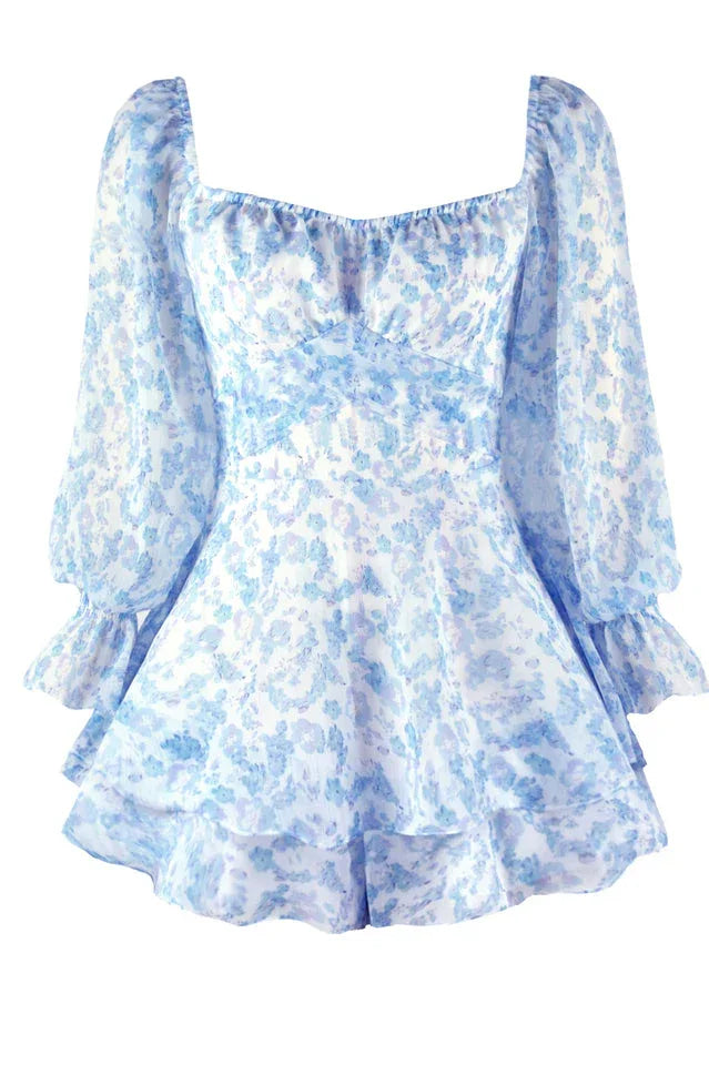 Close-up of the front of a white and blue floral print mini dress with long sleeves and a sweetheart neckline.