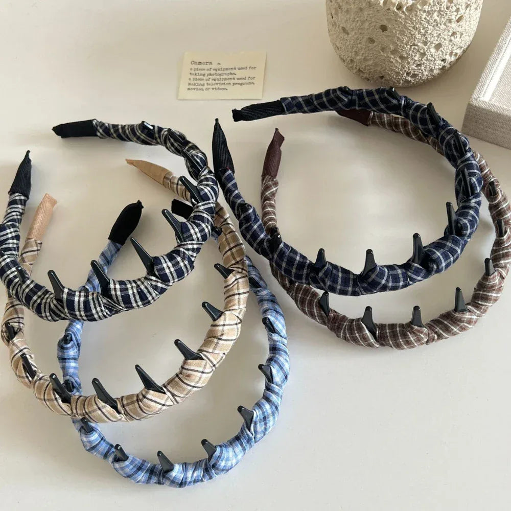 A group of plaid fabric-wrapped headbands with black interlocking teeth on a white surface