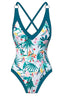 Flat lay of a white one-piece swimsuit with a tropical floral print and teal trim.