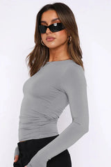 Side view of a woman in a grey long-sleeve cropped top with ruching