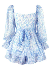 Close-up of the back of a white and blue floral print mini dress with long sleeves and a sweetheart neckline, showing a bow detail.