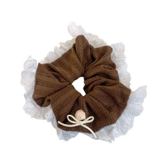 A brown scrunchie with a delicate lace trim and a small pink rose and bow accent, photographed against a white background.