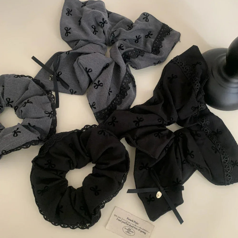 various scrunchies in black and grey with bow patterns and lace trim laid out