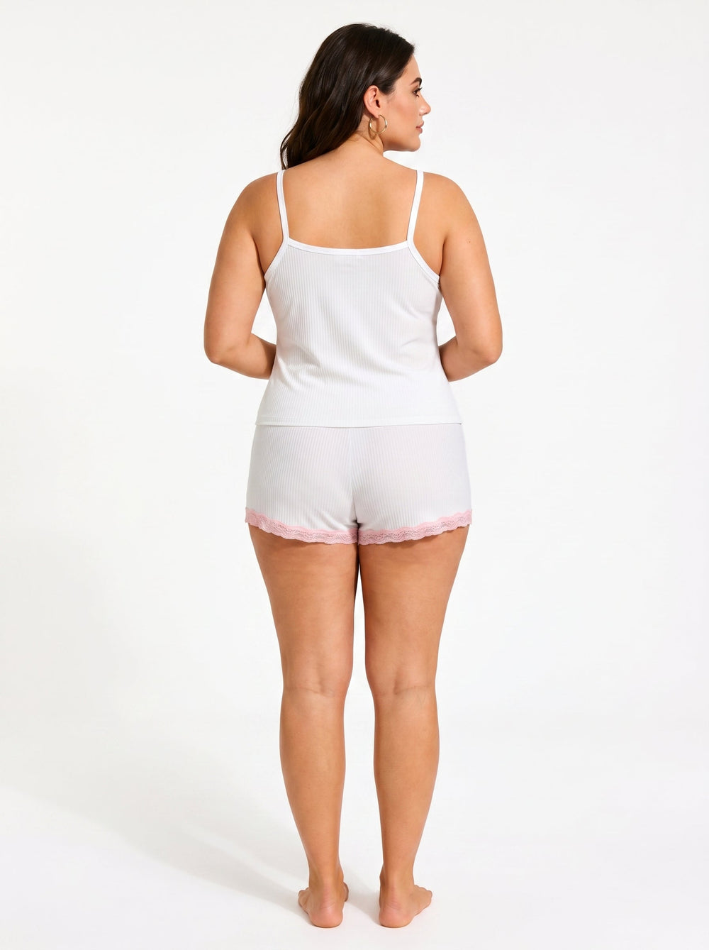Back view of a woman in a white ribbed camisole and shorts pajama set with pink lace trim.