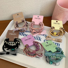 Various hair ties with decorative bows and braided elements shown on a tray.