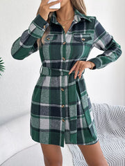 Woman adjusting her hair while wearing a green plaid long-sleeve belted shirt dress