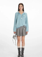 Model wearing a light blue fuzzy knit collared v-neck sweater with a grey pleated mini skirt, white and grey striped socks, and black boots.