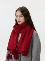 Close-up of a woman wearing a red knit scarf with pom-pom embellishments