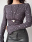 Model wearing a grey long-sleeve top with a white star print and a heart-shaped locket, with a silver handbag.