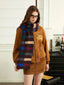 Woman wearing a brown bomber jacket, brown mini skirt, and a multi-colored striped scarf.