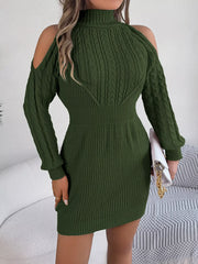 woman holding a white clutch and wearing a green knitted cold shoulder mock neck dress