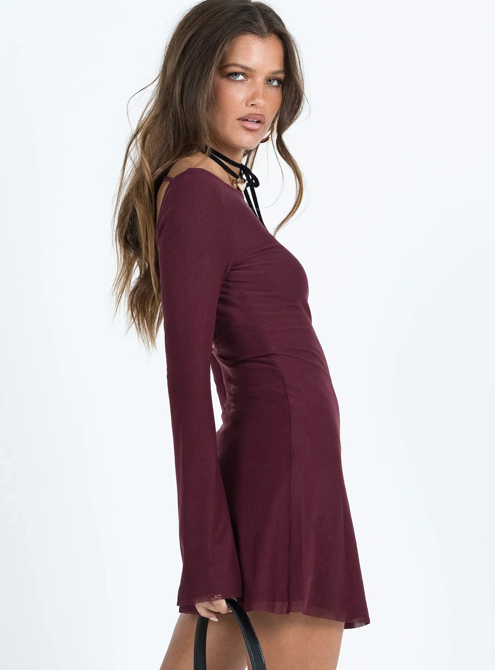 Side profile of a woman wearing a burgundy long sleeve mini dress