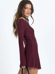 Side profile of a woman wearing a burgundy long sleeve mini dress