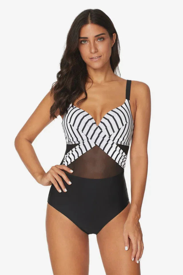 Woman wearing a black and white striped and black one-piece swimsuit with mesh detailing