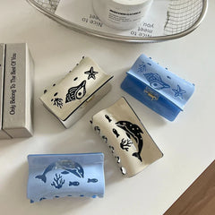 A group of four decorative hair claw clips featuring ocean life designs