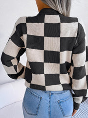 Woman wearing a black and white checkerboard knit sweater with light wash jeans, back view.