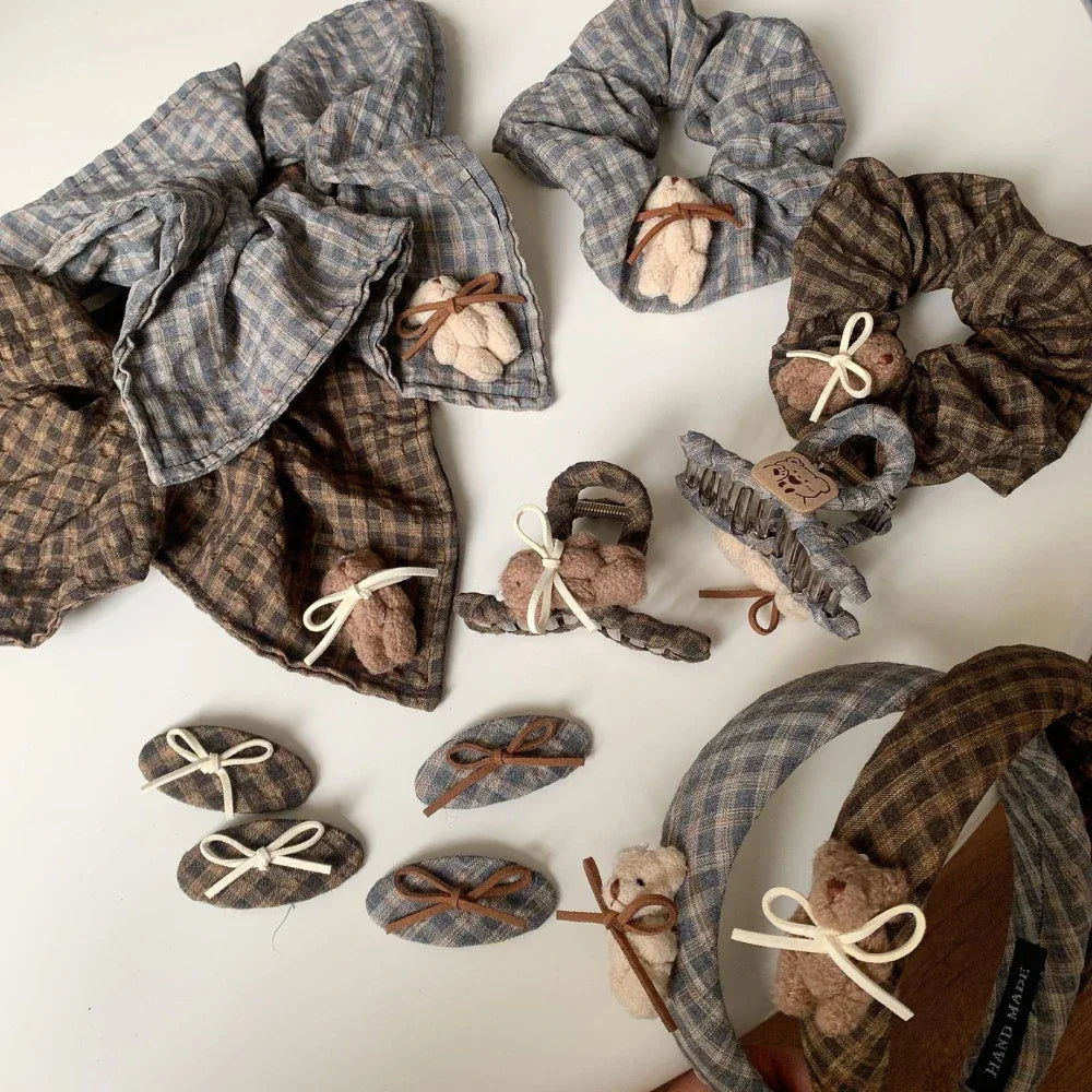 various plaid hair accessories, including scrunchies, headbands, clips, and barrettes, adorned with teddy bears and bows