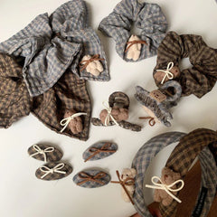various plaid hair accessories, including scrunchies, headbands, clips, and barrettes, adorned with teddy bears and bows