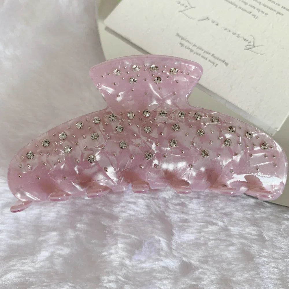 A close-up of a pink marbled claw clip with rhinestones