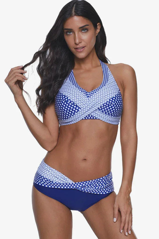 Woman wearing a blue and white polka dot halter neck bikini with high-waisted bottoms, front view.