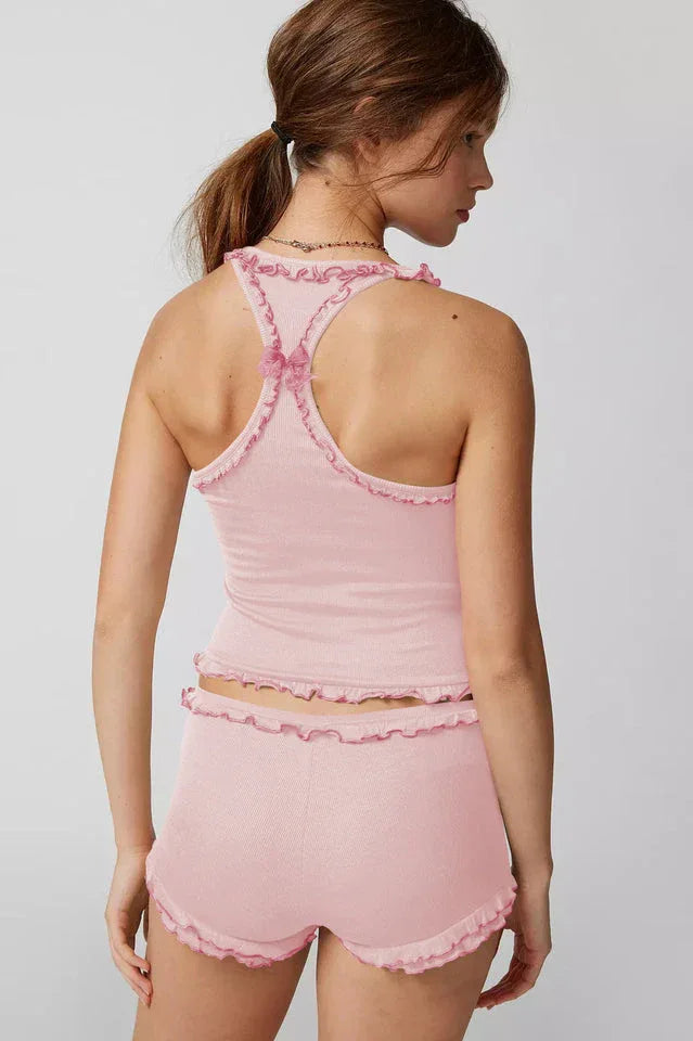 Back view of a woman wearing a pink ribbed knit tank top and shorts set with ruffle trim.
